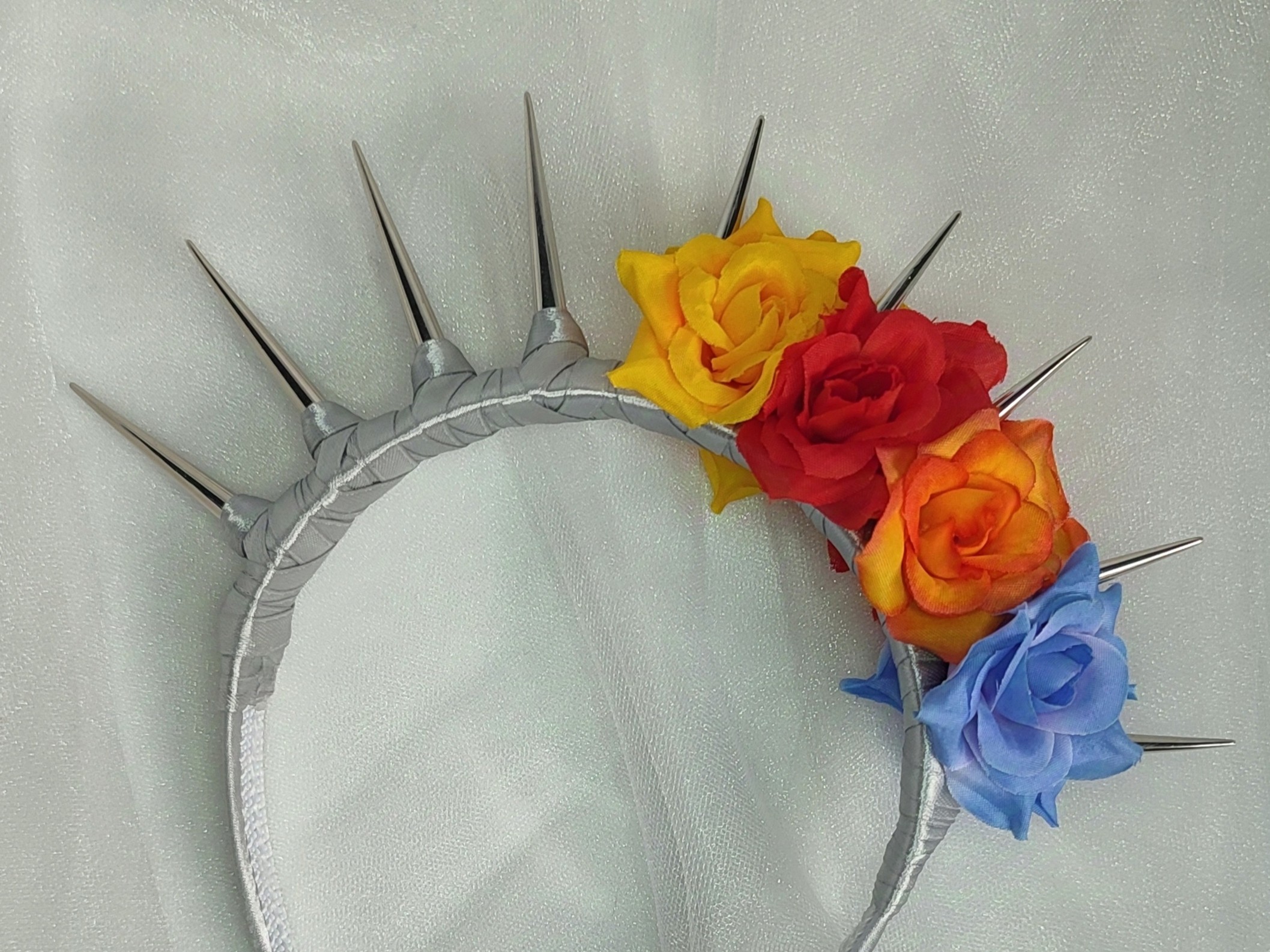 Headpiece with silver spikes and yellow, red, orange and blue flowers.