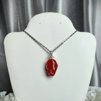 Carnelian pendant wrapped in silver plated wire with chain or cord.
