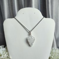 Clear quartz pendant wrapped in silver plated wire with chain or cord.
