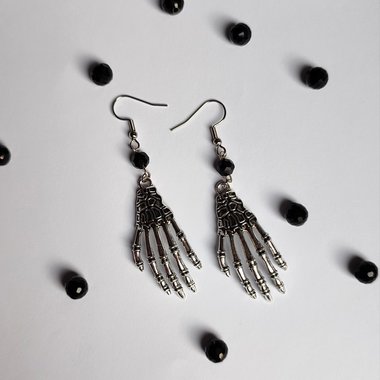 Silver skeleton hand earrings with black crystal beads and fish hooks.