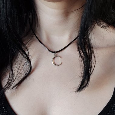 Silver crescent moon choker necklace on black cord.